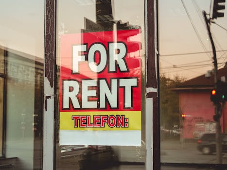 Reflection of a cityscape on a window with a 'For Rent' sign and sunset glow.