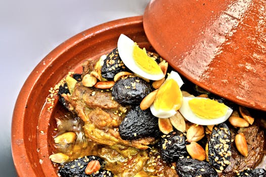 Close-up of Moroccan lamb tagine with prunes, almonds, and boiled eggs in a clay pot.