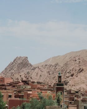 Village aux maisons en terre et minaret au pied d'une montagne rocheuse