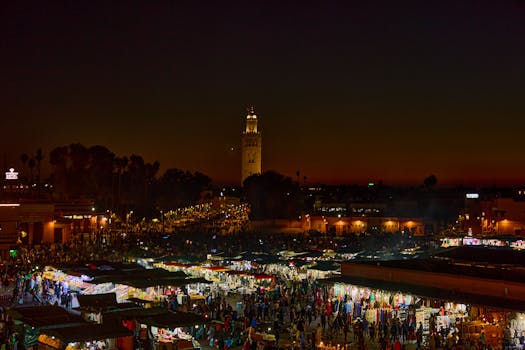 Experience the bustling night market in Marrakesh, Morocco, illuminated against a stunning twilight sky.