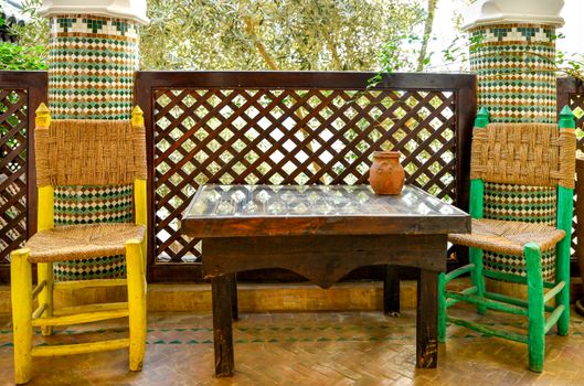 Colorful courtyard with woven chairs and mosaic tiles in Marrakesh, Morocco.