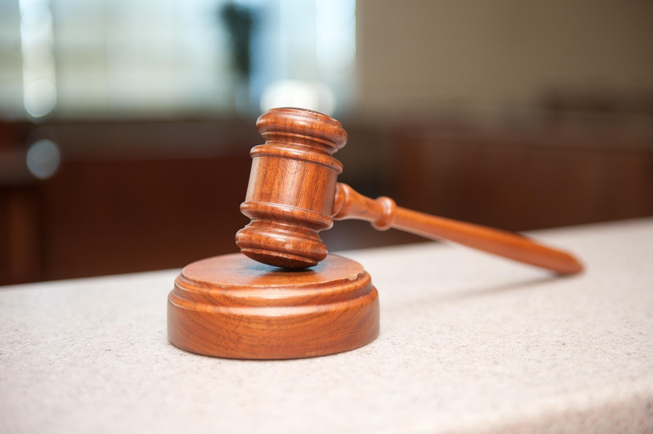 Marteau de juge en bois posé à côté de son socle sur une table blanche