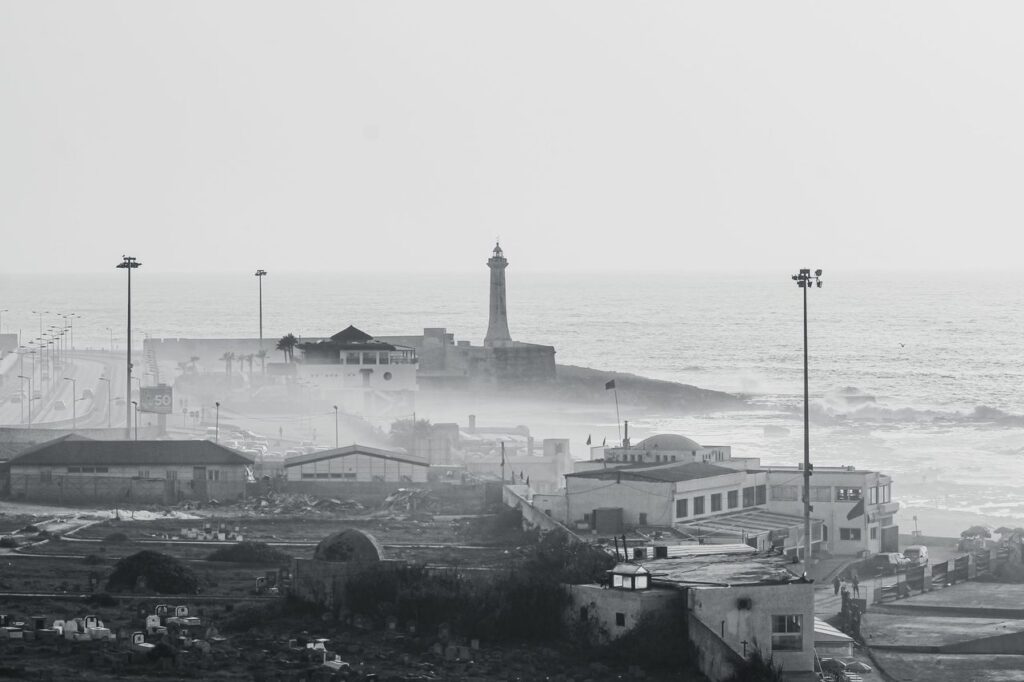A grayscale aerial view capturing the lighthouse and coastal buildings in Rabat, Morocco.