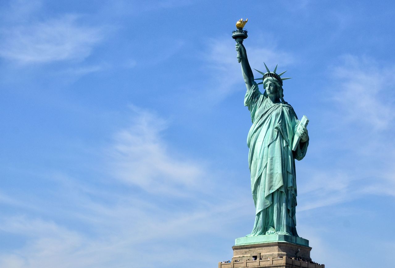 The Statue of Liberty stands tall on Liberty Island under a clear blue sky, symbolizing freedom.